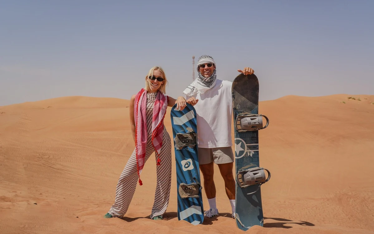 A family walking beside a camel on the sand at a desert camp outside Dubai
