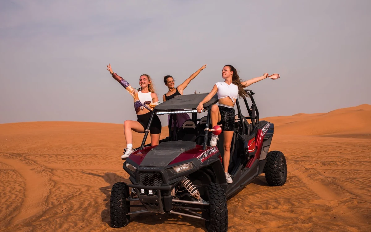 Ein zweisitziger Dune Buggy auf einem Sandrücken geparkt, dahinter verlaufen Spuren den Hang hinunter